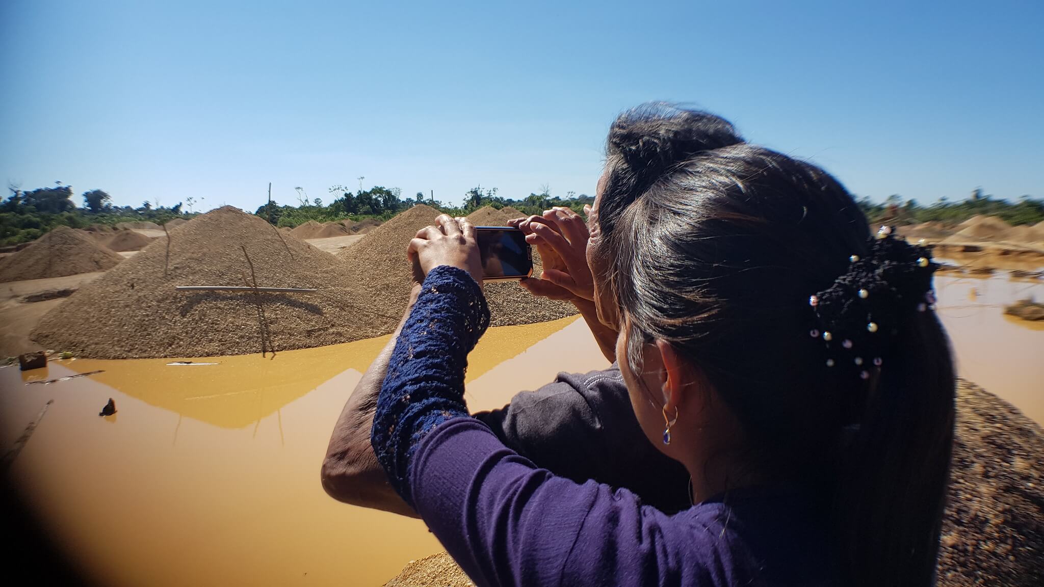 a woman trains another woman to document environmental damage using Mapeo