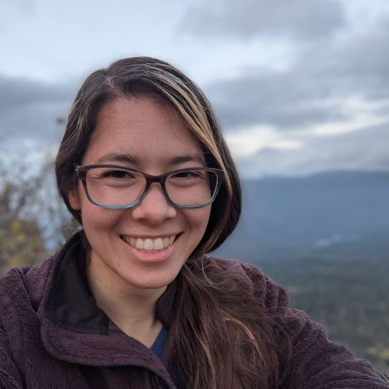 A person with long hair smiles at the camera